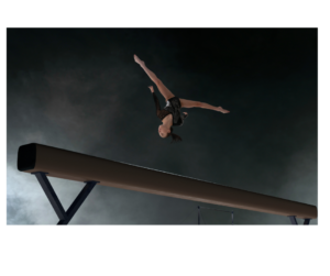 Gymnast performing somersault on beam